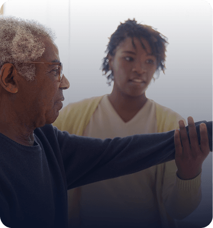Therapist helping an older man with an arm exercise at home