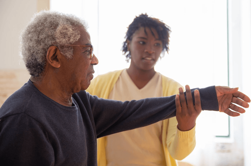 Occupational therapist guiding an older man through an arm exercise