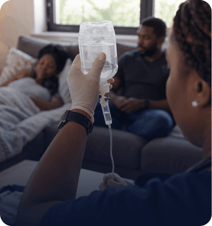 Nurse checking an IV drip for a client recovering at home